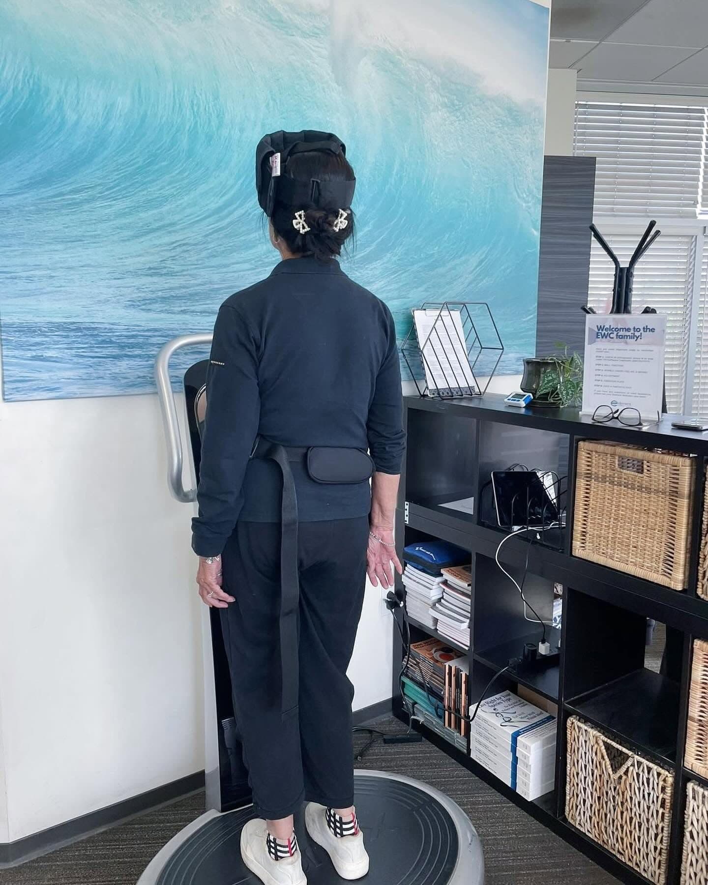 A patient performing guided balance and posture work on a whole-body vibration platform at Element Wellness Center